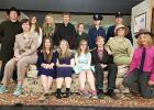 Seated (l to r): Abby Walton as Mr. Witherspoon, Sydney Melby as Abby Brewster, Hannah Kolstoe as Martha Brewster, Kara Longtin as Elaine Harper, Tom Nelson as Mortimer Brewster, Natalie Aakhus as Teddy Brewster, and Remy Ransack as Mr. Gibbs. Back row (l to r): Nick Pahlen as Jonathan Brewster, Jade Person as Dr. Einstein. Tera Qualley as Officer Brophy, Britain Arlt as Rev. Dr. Harper, Heather Longtin as Lieutenant Rooney, Jayden Iverson as Officer Klein, Dede Walton as Officer O’Hara. 