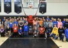Boys and girls basketball players at RLCC standing by the new shooting machine which was made possible from donations by individuals and businesses.