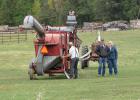 Ron and Marian Vold of Pinewood stopped by the David Mast residence to see how the threshing operation of the specialty grain was going. Power for the threshing machine was from an old tractor shown behind the Vold’s.