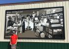 The mural was hung on the side of the Grygla Coop Store on August 19th. Beau Bakken stands next to his creation.